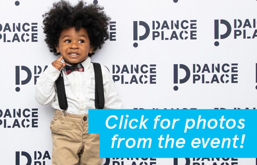 A long boy with an afro poses adorably in front of a step-and-repeat